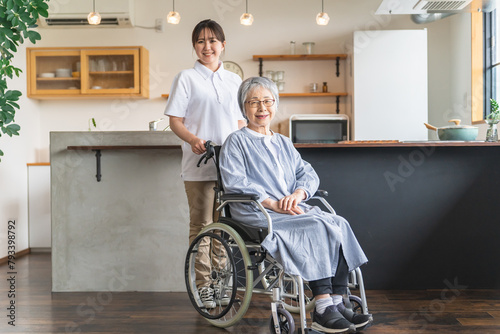 車椅子に座るシニア女性と介護士・理学療法士・介護スタッフの女性 