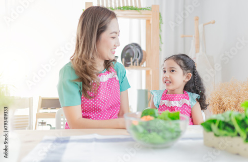 attractive asian children and her mother cooking and eating organic vegetables salad, family time, child health nutrition
