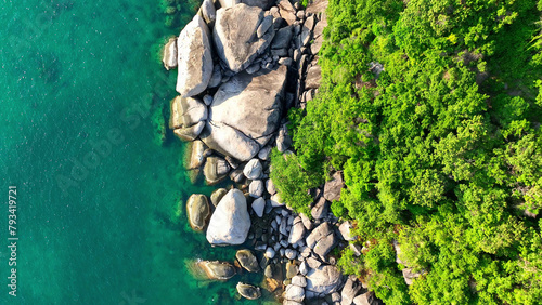 Over the turquoise ocean, a drone captures the enchanting blend of rocky shores and verdant forests on a stunning island. Drone aerial view. Gulf of Thailand. Tropical background.  © Punyawee
