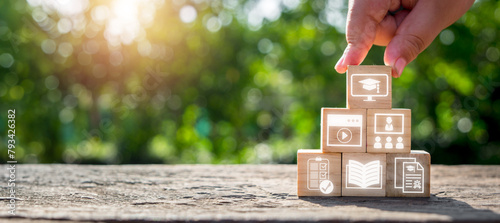 Online education concept, Hand holding wooden block on desk with course, technology, study, teacher, training and learn icon on virtual screen.