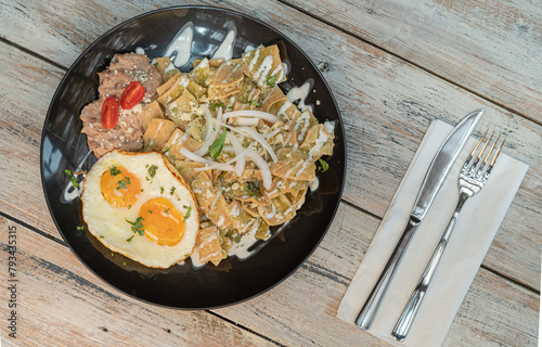 chilaquiles verdes con huevo estrellado encima y frijoles.
