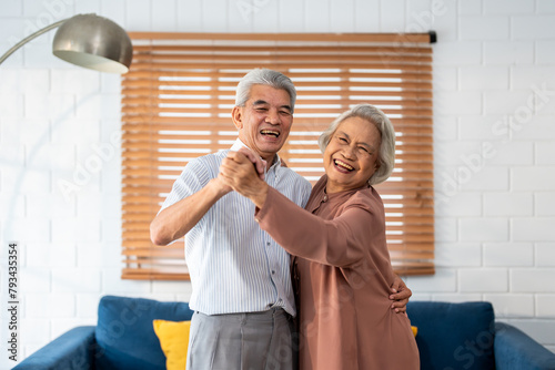 Portrait of Asian senior couple dance together in living room at home. 
