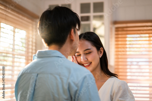Asian young man and woman looking at each other in kitchen at home. 
