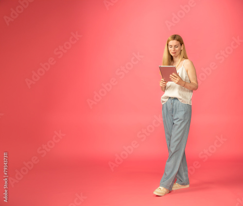 full-length girl with a tablet on a pink background