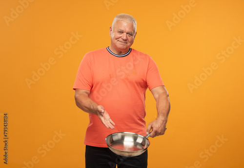 elderly man holding an empty frying pan