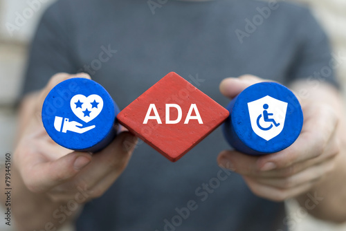 Man holding blocks with icons sees abbreviation: ADA. ADA Americans with Disabilities Act concept. Disability Law Social Services. © wladimir1804