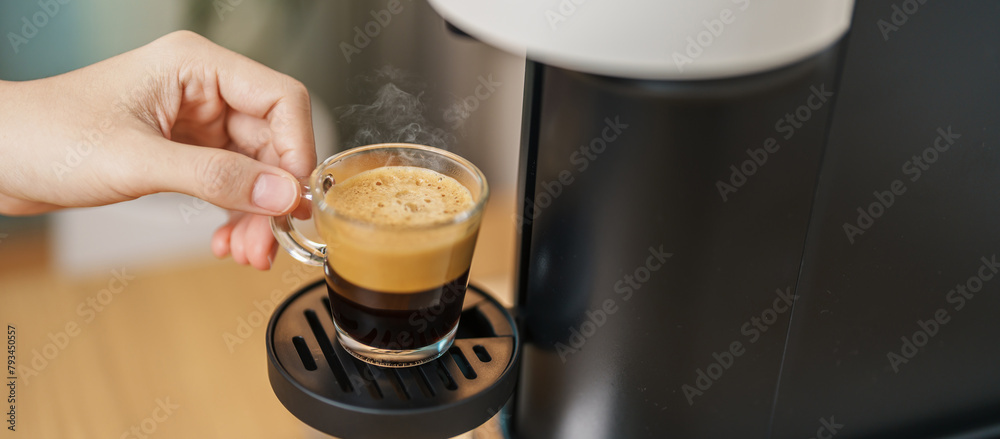 Espresso cup with steam and froth during Coffee making Coffee by Coffee Maker Machine on wood table bar. Cafe shop, Daily beverage drink at Home, Apartment and Office concept