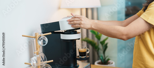 hand making Espresso Coffee by Coffee Maker Machine with Capsule of roasted coffee bean on wood table bar. Daily beverage drink at Home, Apartment and Office concept