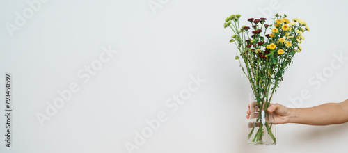 Woman hand hold Colorful flowers bouquet in mason jar on background. Happy day with fresh flower