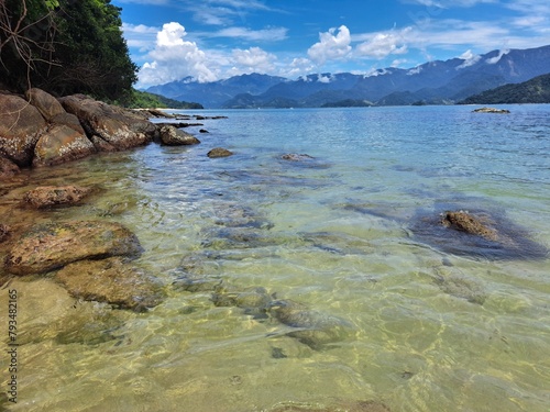 Pelado Island in Paraty, mountains in the background,sky with clouds, large rocks, and calm sea. Natural swimming pool and warm water photo