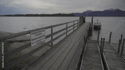 Lake Chiemsee, Chiemgau, Bavaria, Germany. Beautiful sunset on Bavarian lake Chiemsee with view of mountains and boat from pier. Chiemgau and Schliersee Alps. Priener Scharen.  photo