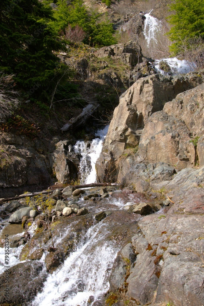 Water cascading and splashing down and around rocky cliff face, partially in shadow. Water cascading and splashing down and around rocky cliff face, partially in shadow.