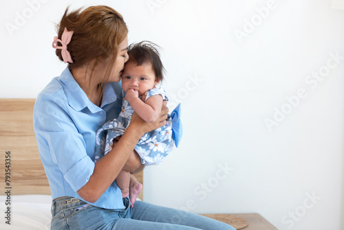 Mother holds and comforts her little daughter on the bed at home, Mother's Day concept