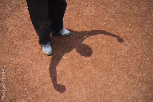 Daytime silhouette of a man flexing his muscles showing strength on the ground 