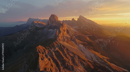 Aerial view of a mountain range at sunrise, the peaks illuminated with golden light against the shadowed valleys © boxstock production