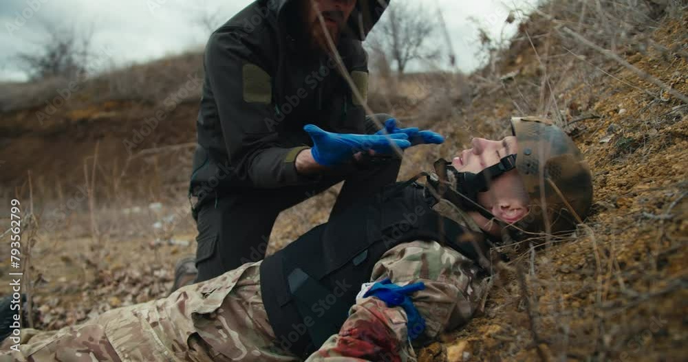 A confused male medic in a green uniform provides first aid to a ...