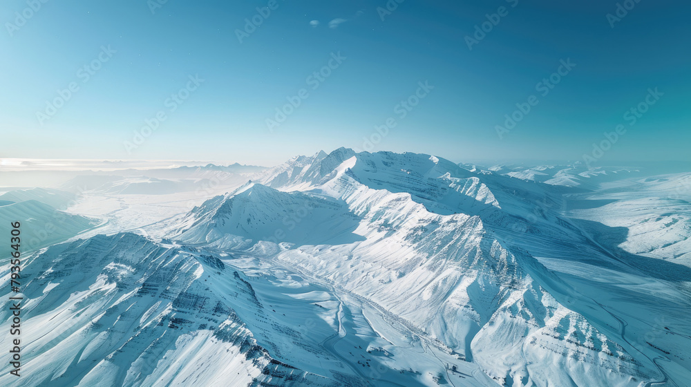 Naklejka premium Aerial view of majestic beauty of a snow-capped mountain range under a clear blue sky