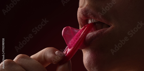 Mouth of sensual girl with condom. Protection, safe sex and Contraceptive concept. Condom in the mouth of women, close up. Open mouth and sexy lips, lick condom. Condom in mouth of sexy women. © Volodymyr