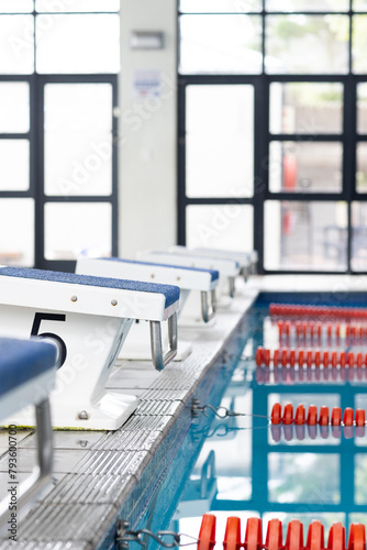 Swimmers preparing to dive into swimming pool, focusing on their start, copy space