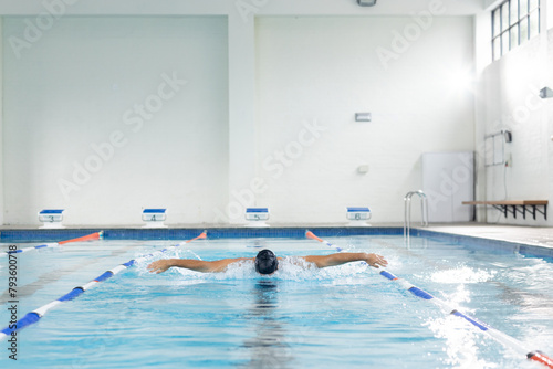 Biracial young female swimmer is training indoors in a pool, copy space