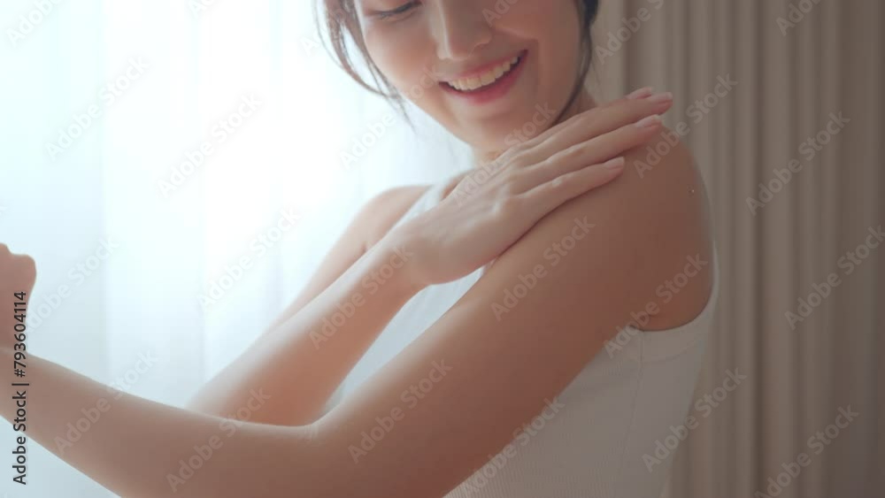 Happy young asian woman applying body lotion and skincare cream on arm, Beauty skin concept