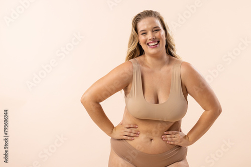 Plus size model with blonde hair and freckles on beige background, copy space photo