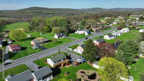 Traffic on rural intersection in scenic landscape with houses and homes. Spring day with sunlight and green hills in background. United States, USA. Aerial wide lateral flight. photo