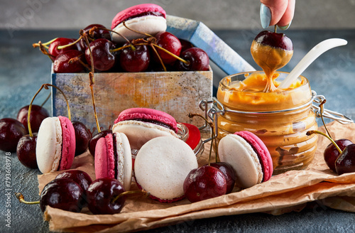 A white plate with macarons and cherries on a table