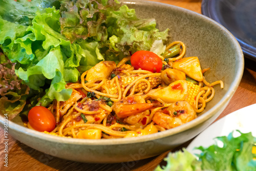 A bowl of spaghetti noodles with shrimp squid and tomatoes