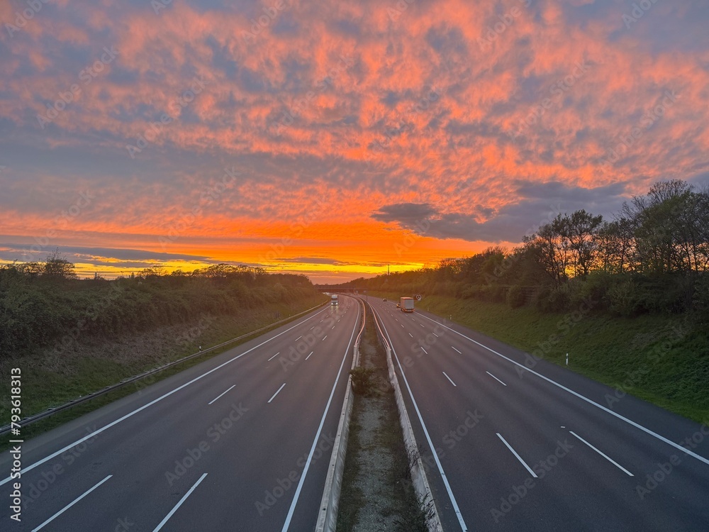 German highway A2 from above, bright red sunset sky panorama with fleece colorful clouds. Near Langenhagen Godshorn, district Hanover, Lower Saxony, Northern Germany.