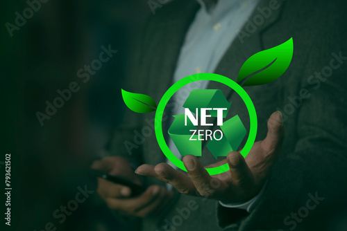 Human holds a green recycling symbol with the words net zero. CO2 level gauge percentage reduced to 0 Net Zero. Greenhouse gas emissions target, reduce carbon footprint.