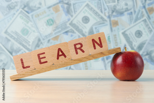 A conceptual image of investing in education, featuring LEARN spelled out on wooden blocks balanced on apples, with a background of various currency notes