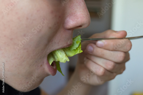 Detail of a Boy's Mouth Biting Salad Leaves