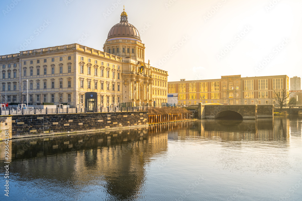 Golden morning sunlight bathes the Berlin Palace and Humboldt Forum, reflecting on the calm waters. Berlin, Germany