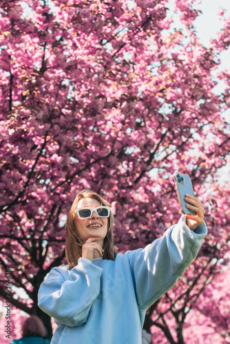 happy woman taking selfie on the phone in front of blooming sakura © phpetrunina14
