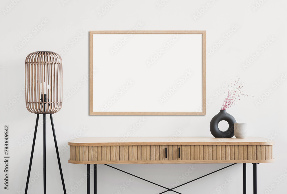 Fototapeta premium Empty horizontal frame mockup in modern minimalist interior with plant in trendy vase on white wall background. Template for artwork, painting, photo or poster