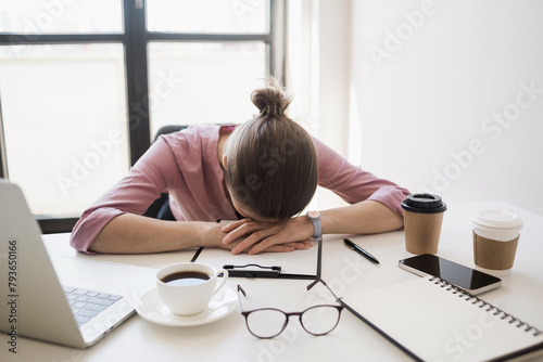 Tired and overworked business woman. Young exhausted girl sleeping on table during her work using laptop, digital tablet and smartphone. Entrepreneur, freelance worker or student in stress concept © kite_rin