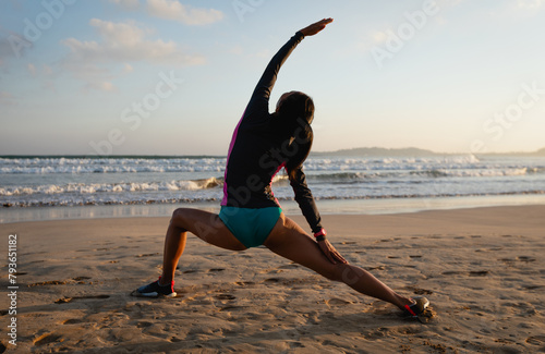 Woman surfer warming up on sunset beach