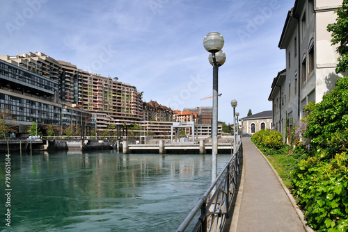 Geneva, Switzerland, Europe - Rhone river, footpath leading to hydroelectric power station and BFM theater building, apartments skyscrapers along Quai du Seujet, Jonction district
