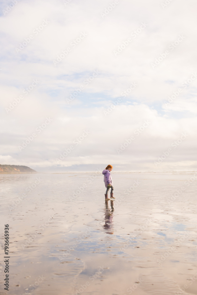 Redhead girl walking along shore at low tide Redhead girl walking along shore at low tide