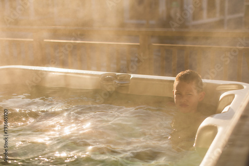 Child unwinding in a hot tub during a golden sunset photo