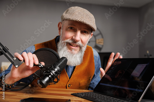 Studio podcast avec un micro et un ordinateur tablette et un homme souriant au look stylé et vintage avec une barbe hipster