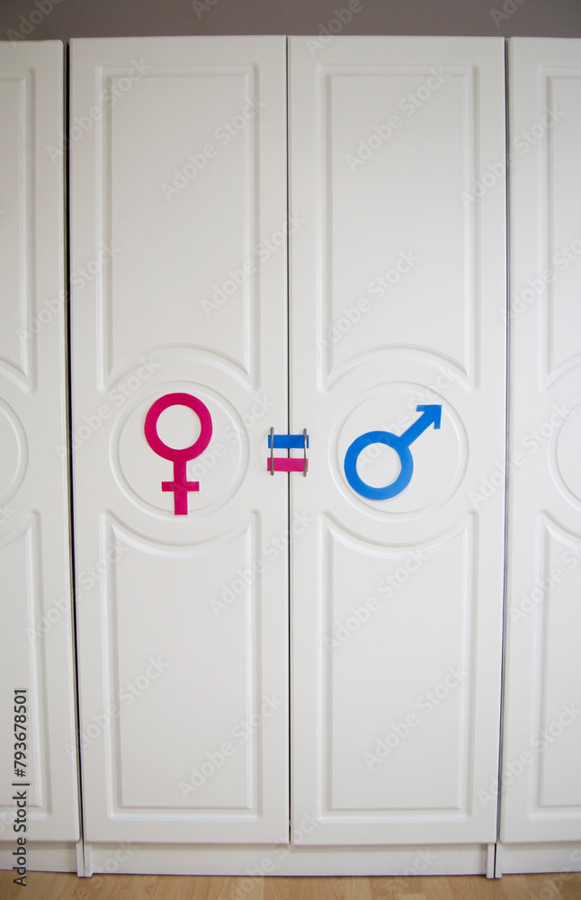 Fototapeta premium LGBT symbol. paper signs with male and female symbols painted in lgbt rainbow colors on white door.White wooden wardrobe.Rights and gender equality, LGBT Pride Month in June.