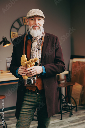 Portrait d'un photographe créatif et original  de type hispter très élégant et stylé avec un manteau un béret et un gilet dans un atelier créatif © Chlorophylle