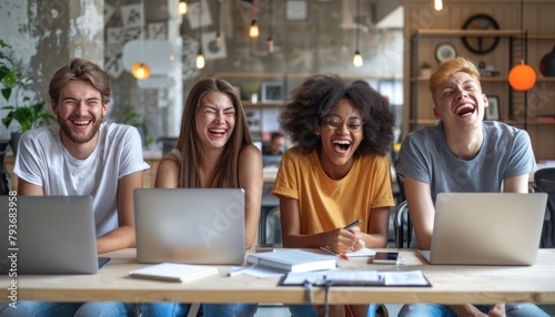 A group of young people sharing fun snapshots at a table with laptops