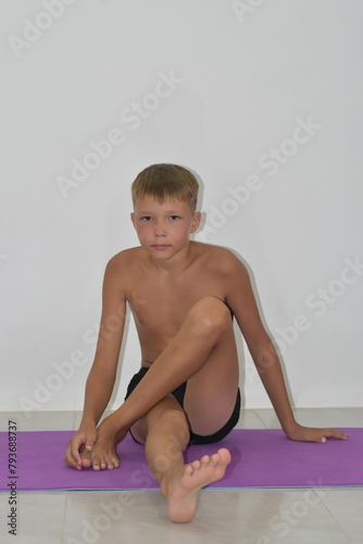 Blond boy in black shorts on a yoga mat.