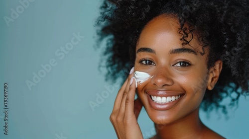 Skincare, studio portrait, and smiling woman applying self-care, sunscreen, or hydration cream. Facial regimen, dermatology ointment, and spa wellness individual on blue background.