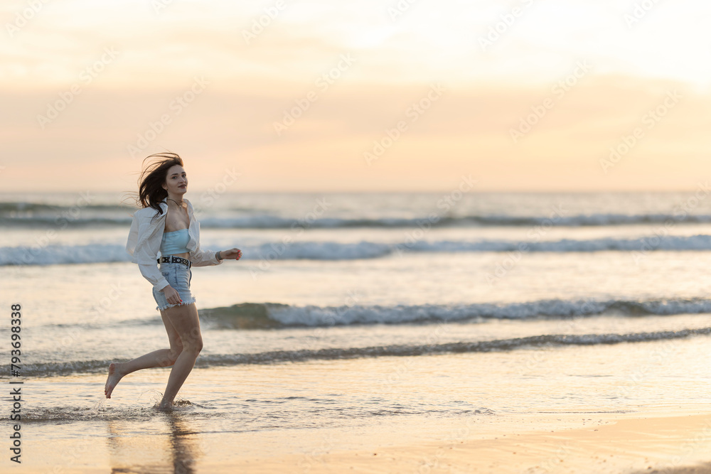 A woman is running on the beach with the sun setting in the background