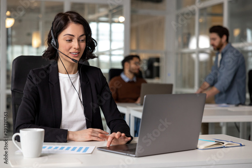 Young friendly operator woman agent with headsets working in call center in contemporary office