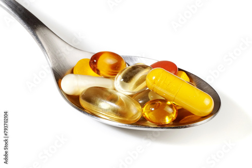 Pills on a spoon on white background